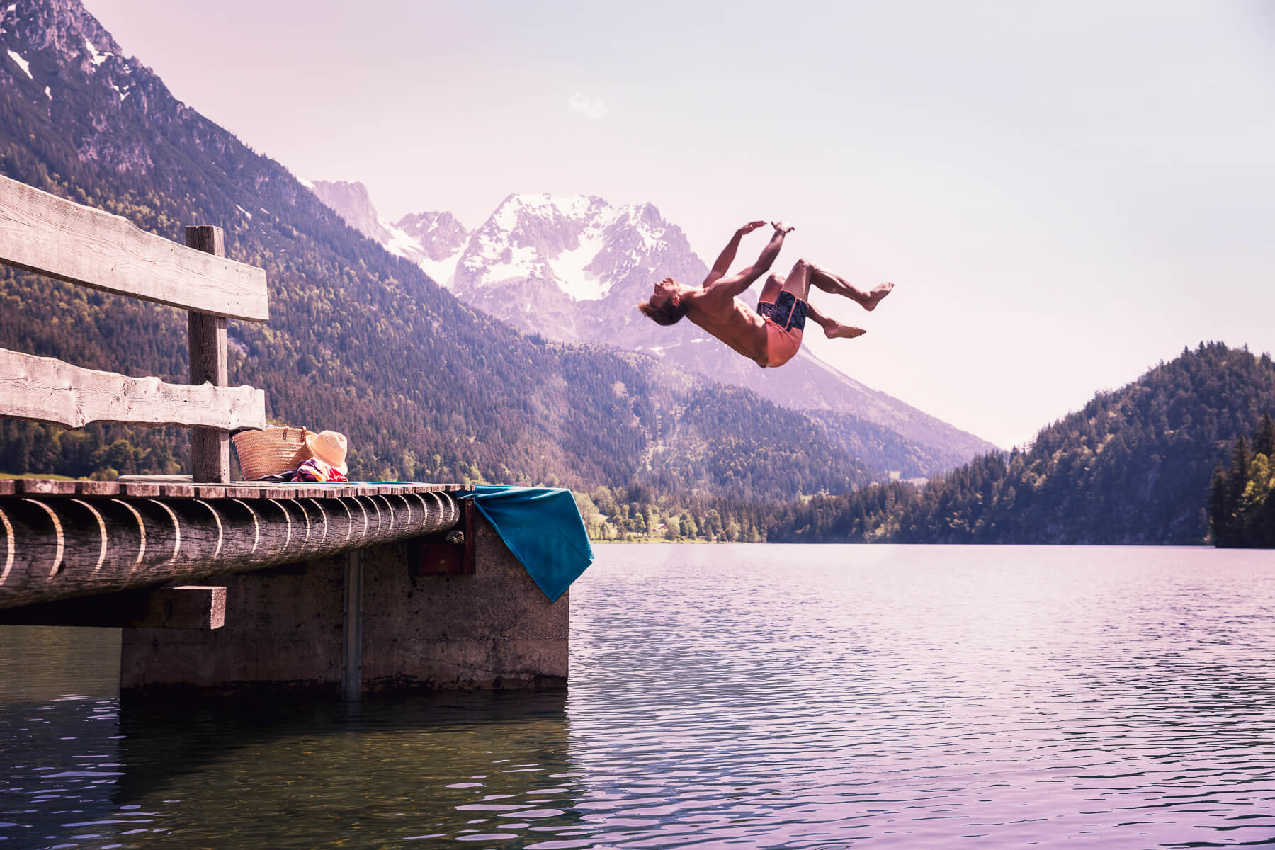 Ein Mann macht ein Gainer in einem Bergsee. Tirol Lodge - Derek Henthorn - Fotograf München
