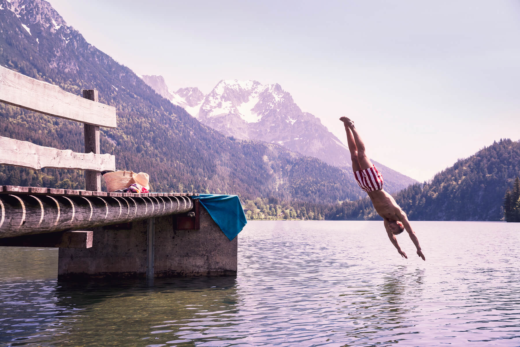 Ein Mann macht ein Kopfsprung in einem Bergsee. Tirol Lodge - Derek Henthorn - Fotograf München