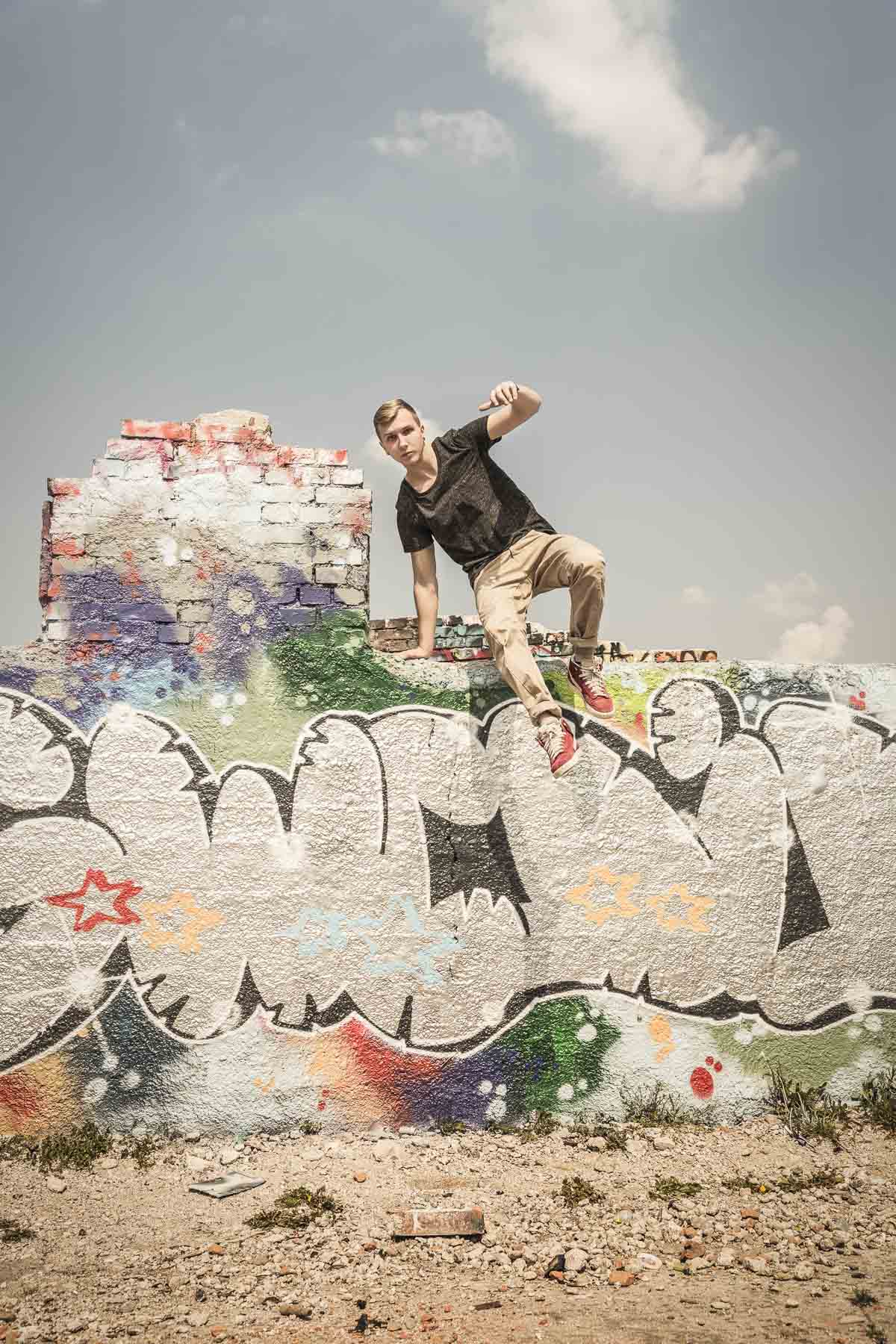 Teenager springt von einem Mauer. Lifestyle - Derek Henthorn - Fotograf München